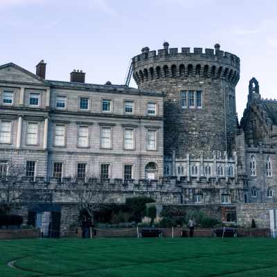 A historic stone castle with a round tower and adjacent classical-style building.