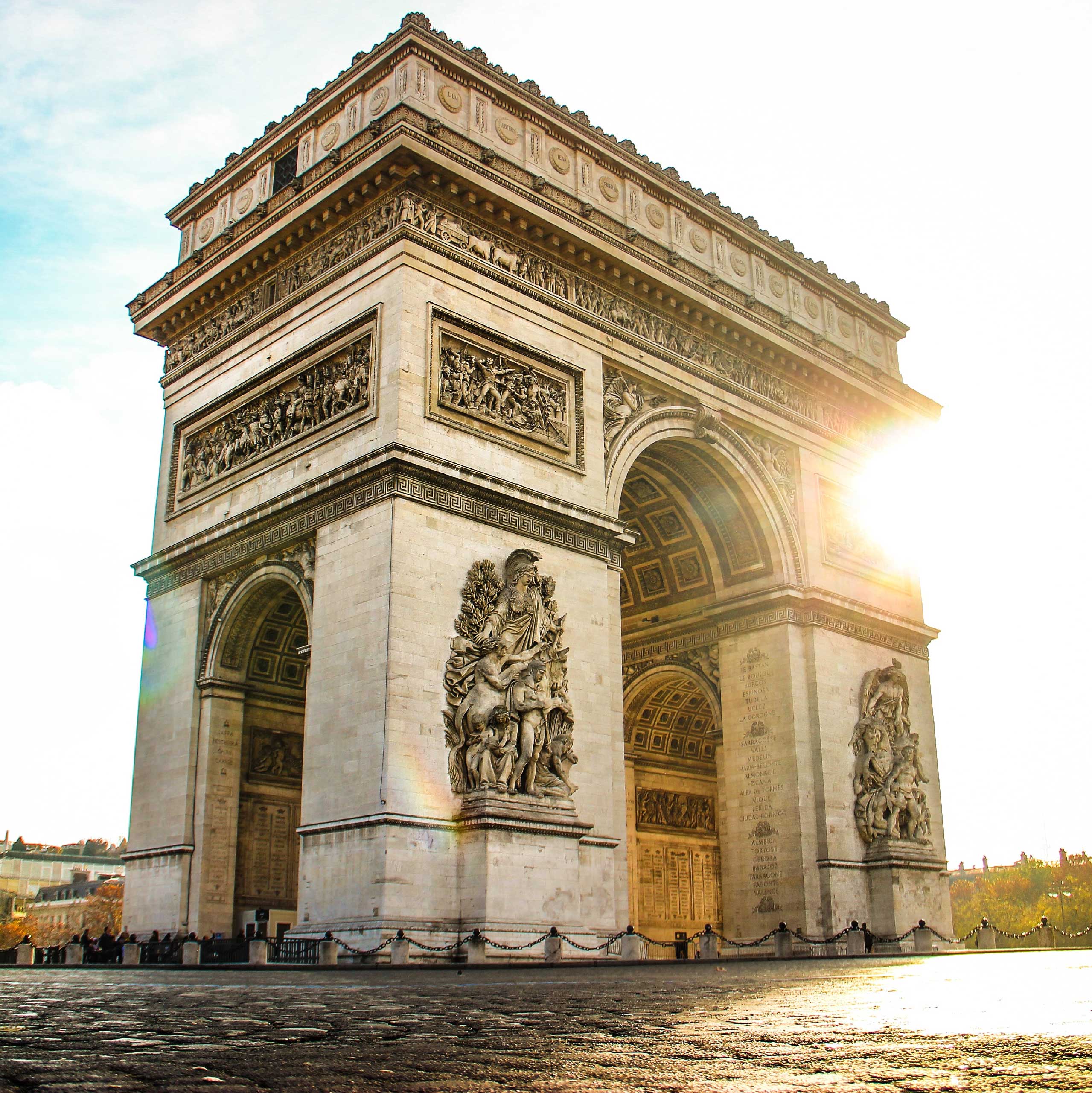 The Arc de Triomphe in Paris, illuminated by sunlight, showcases intricate sculptures and carvings.