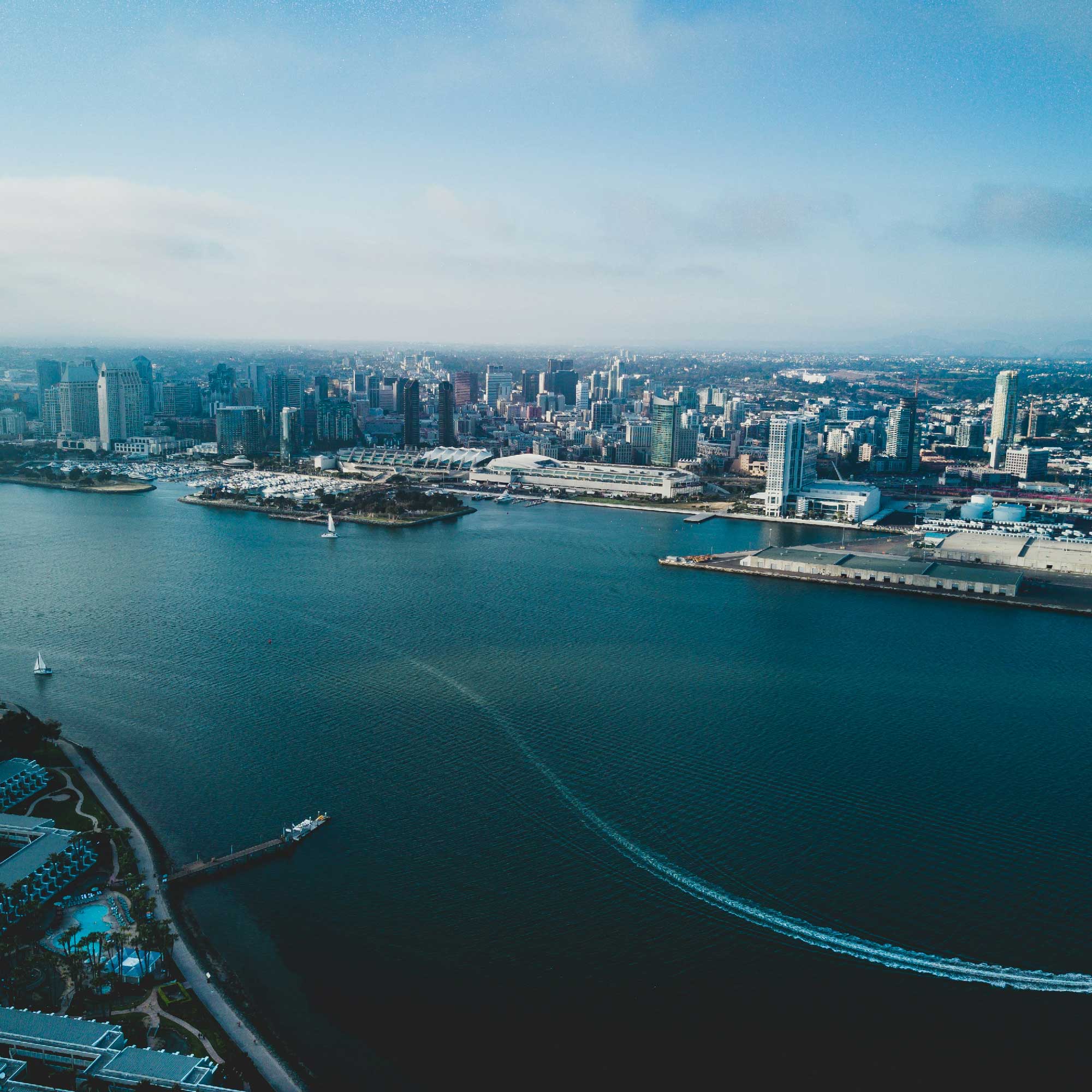 Aerial view of San Diego skyline, waterfront, and marina under a clear blue sky.