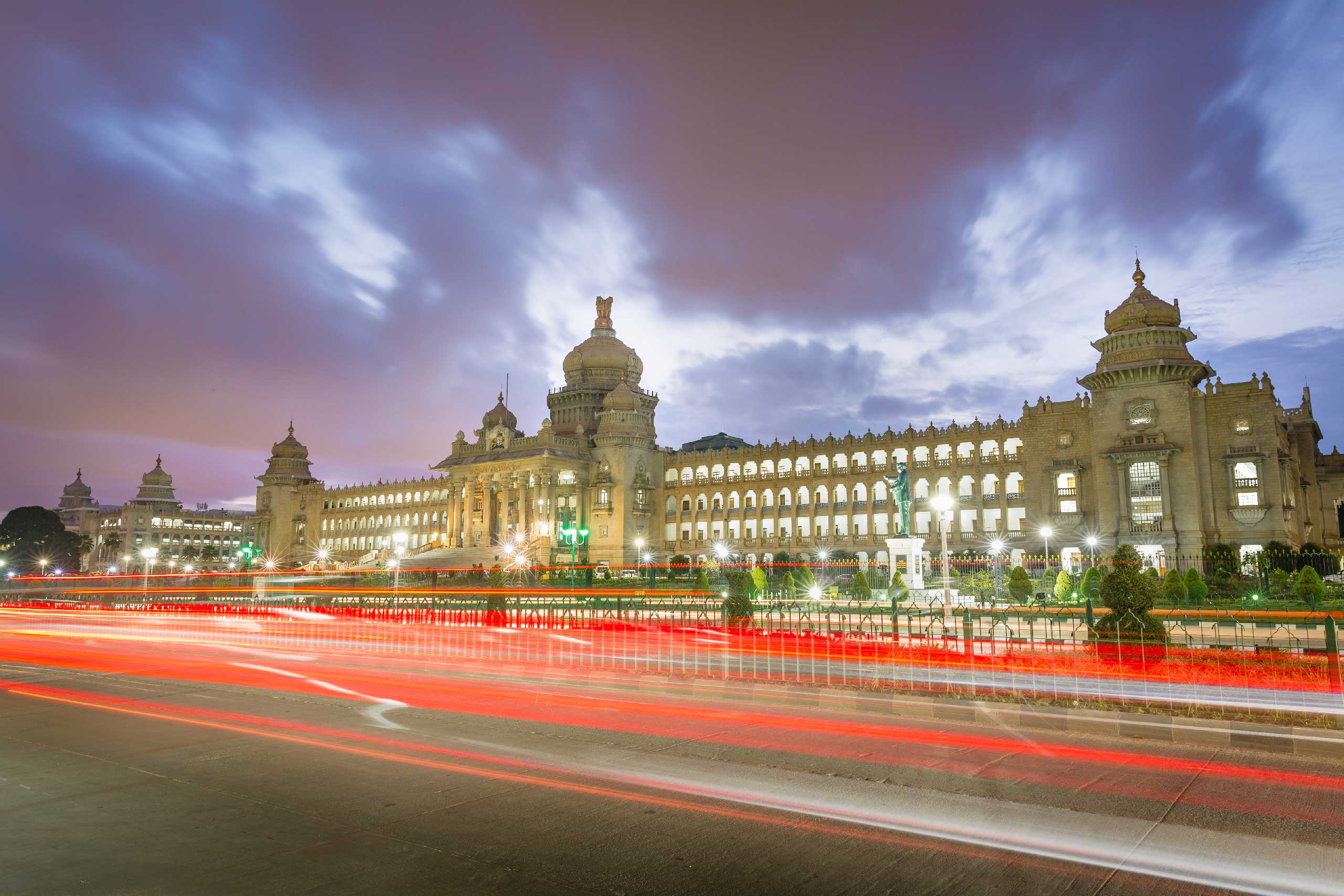 Vidhana Soudha, Bengaluru, illuminated at dusk with light trails in the foreground.
