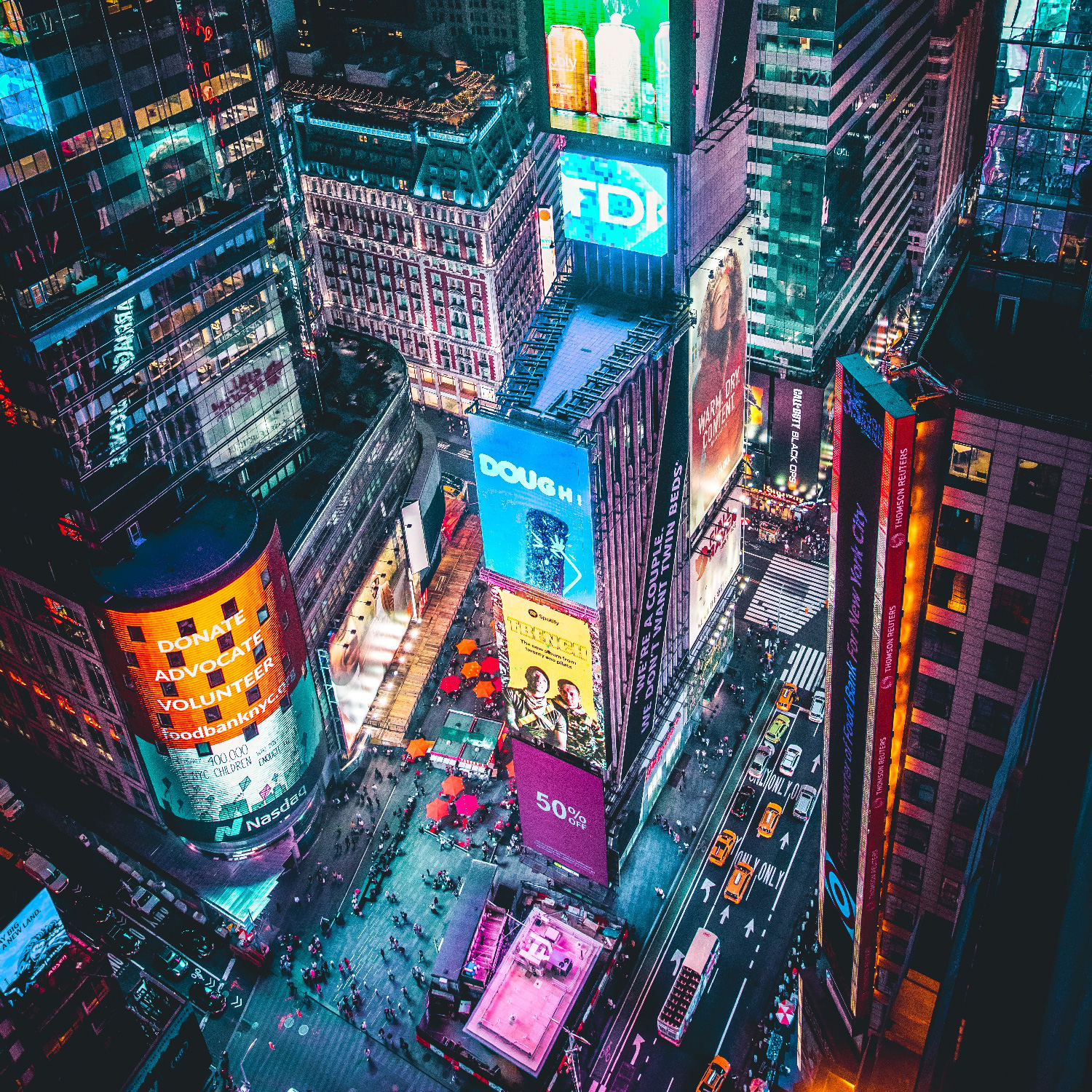 A vibrant aerial view of Times Square at night, illuminated by colorful billboards and city lights.