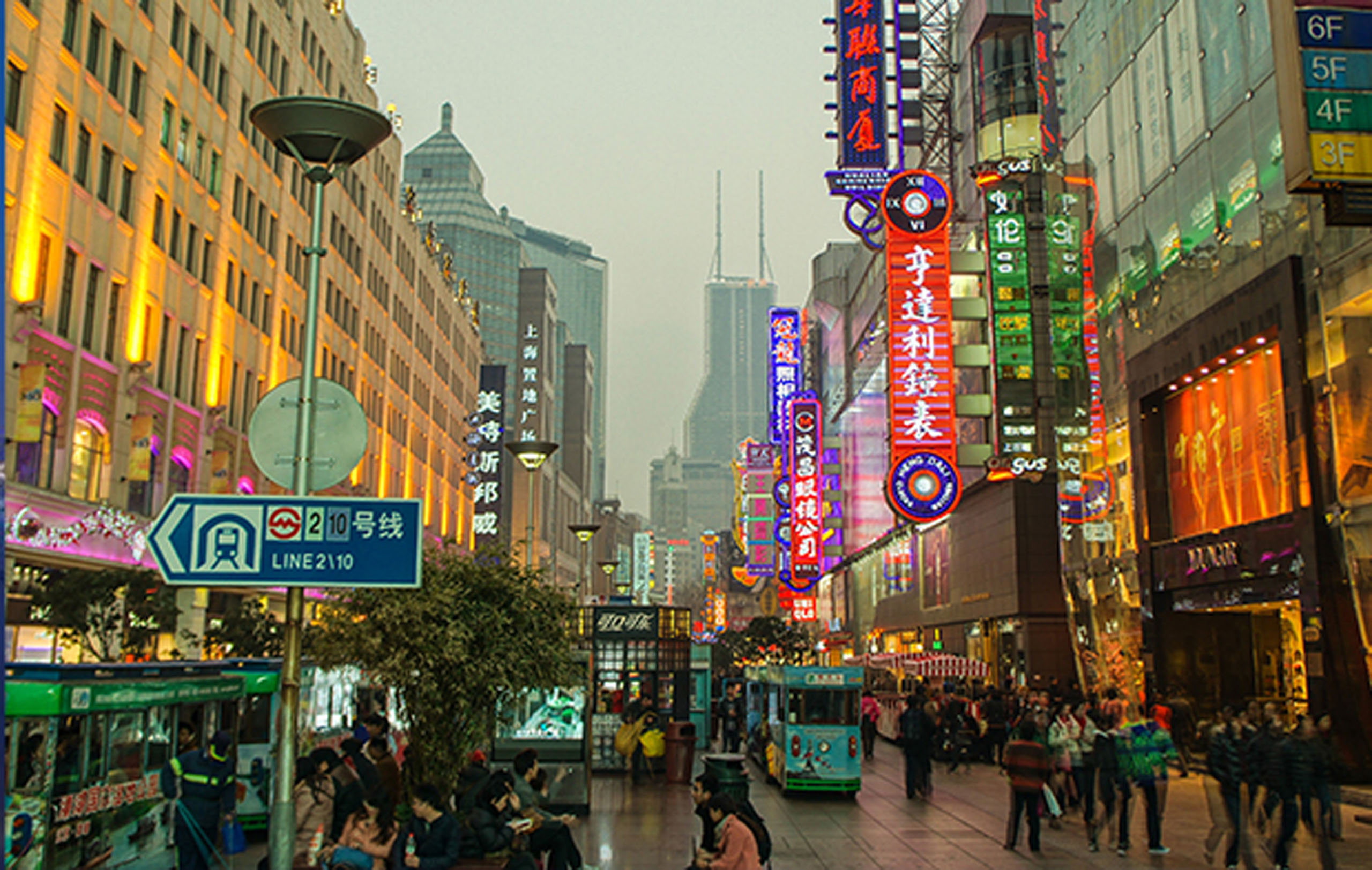 A bustling urban street with vibrant neon signs, modern buildings, and a metro line indicator.