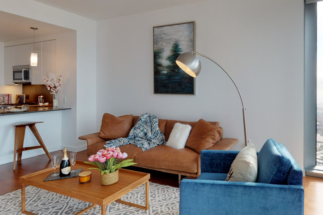 Modern living room with a brown sofa, blue chair, wooden table, and sleek floor lamp.