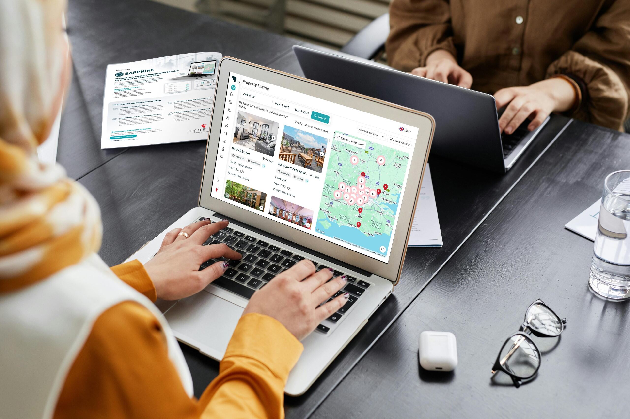 A person searches property listings on a laptop, with a map view and detailed options displayed.