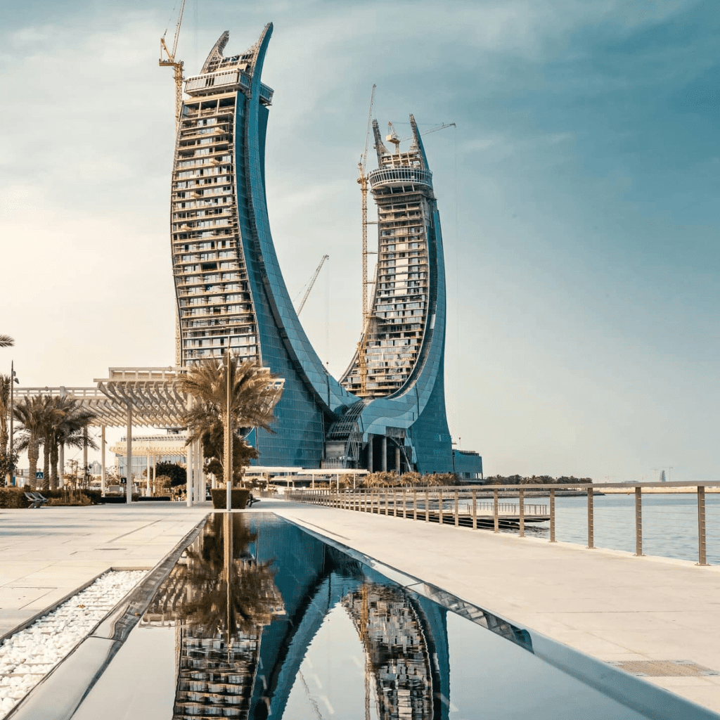 Iconic crescent-shaped skyscrapers under construction, reflecting in a sleek water feature.