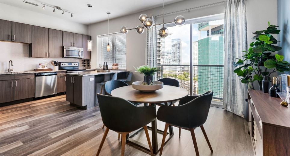 Modern kitchen and dining area with sleek furniture, large windows, and cityscape views.