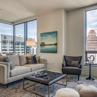 Modern living room with neutral tones, large windows, and minimalist decor.