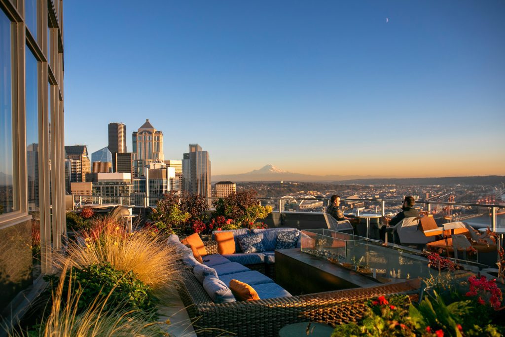 Rooftop lounge with city skyline, Mount Rainier, and sunset views in a modern urban setting.