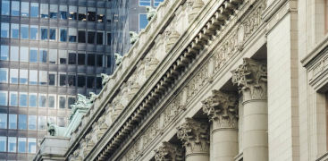 Classical columns with ornate capitals contrast against modern glass skyscrapers in the background.