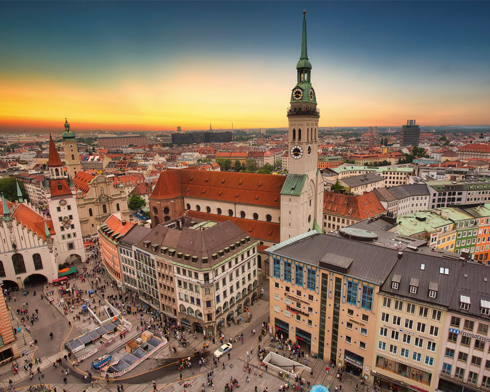 A vibrant cityscape of Munich's Marienplatz with historic architecture at sunset.