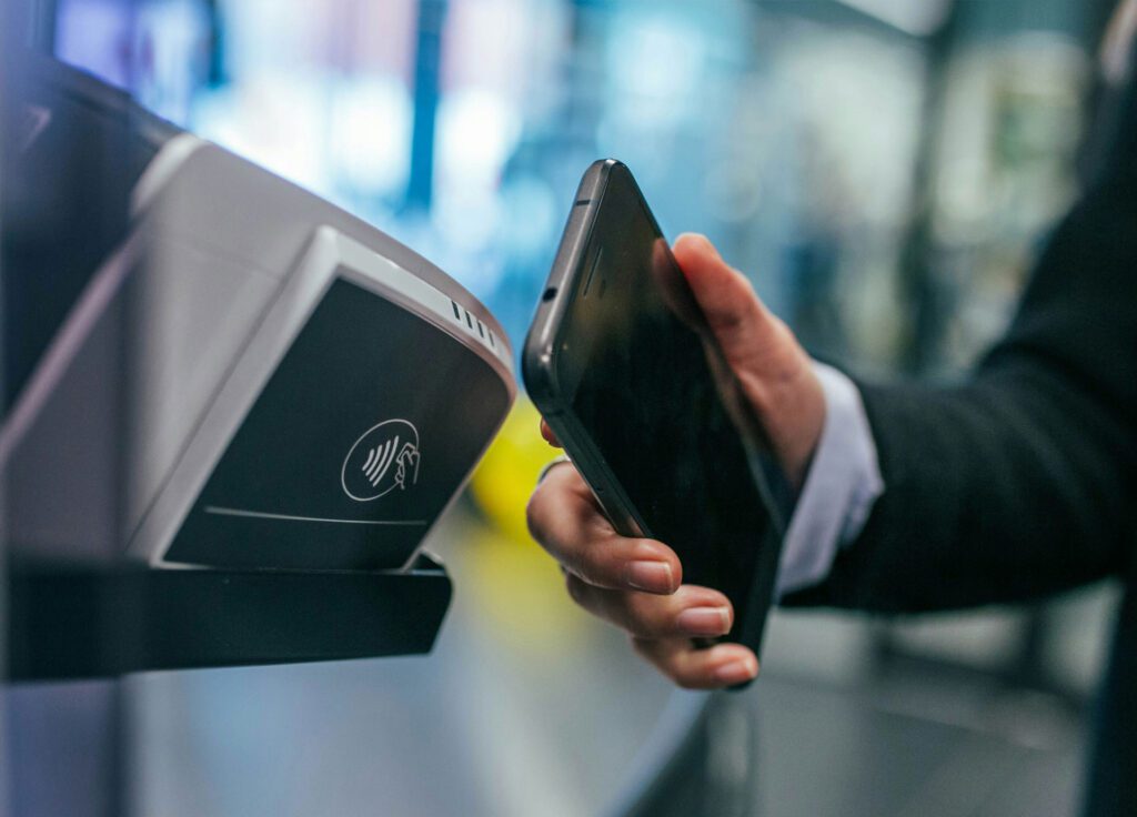 A person uses a smartphone for contactless payment at a terminal with NFC technology.