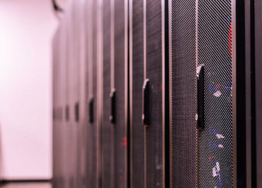 A row of black server racks in a data center with mesh doors and visible hardware components.