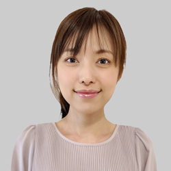 A woman with brown hair wears a light-colored blouse featuring pleated details and puffed sleeves.