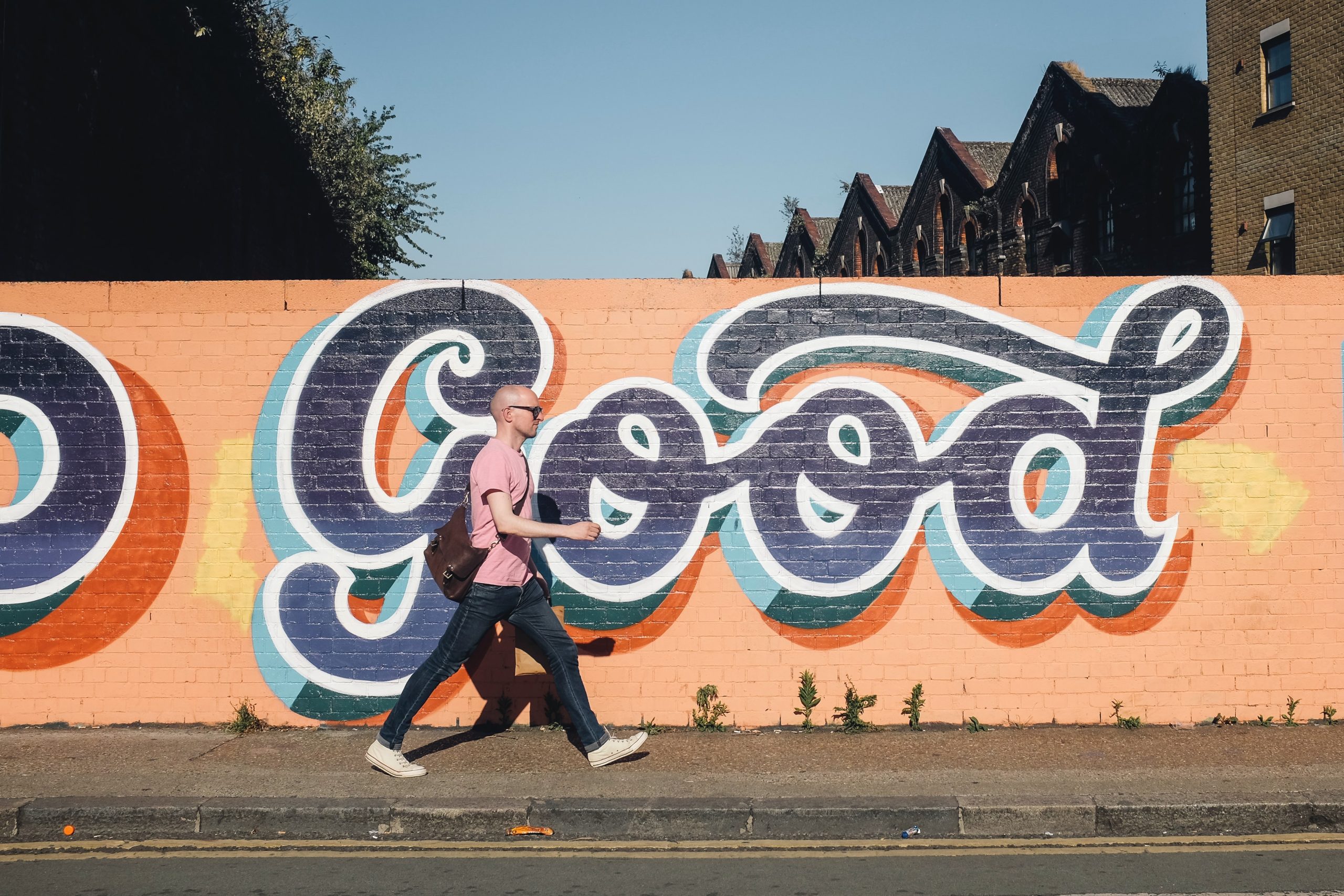 Man walking alongside a mural.