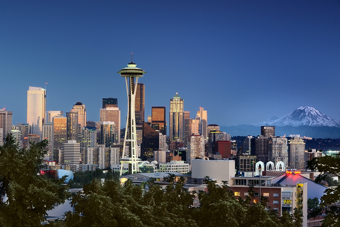 Seattle skyline at dusk, featuring the Space Needle and Mount Rainier in the background.