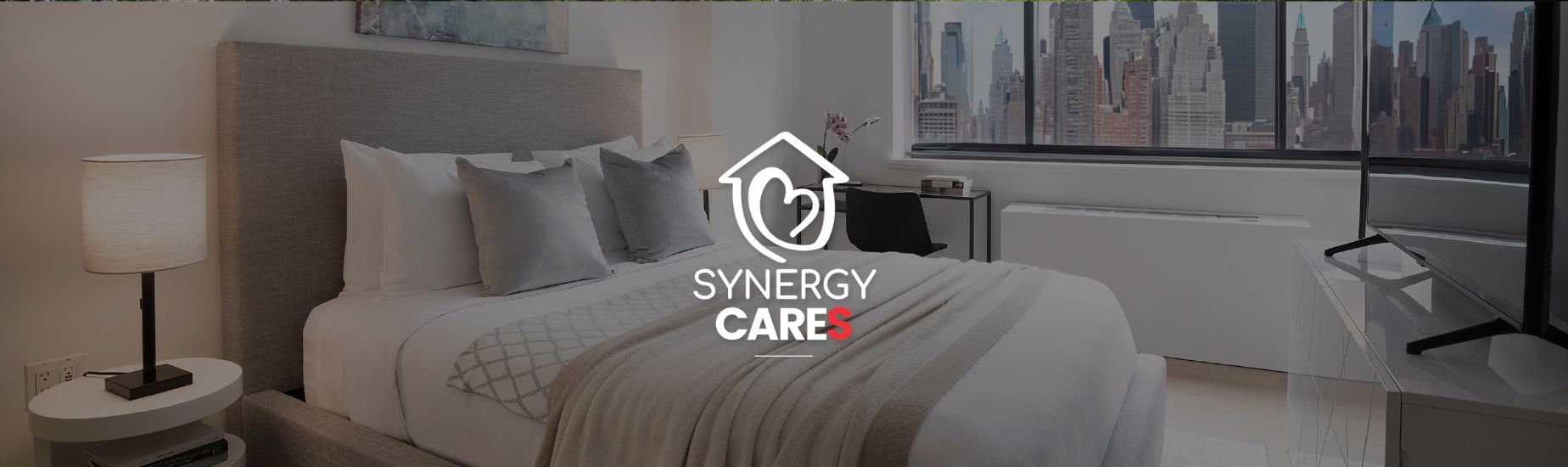 Modern bedroom with city skyline view, neutral decor, and Synergy Cares logo overlay.