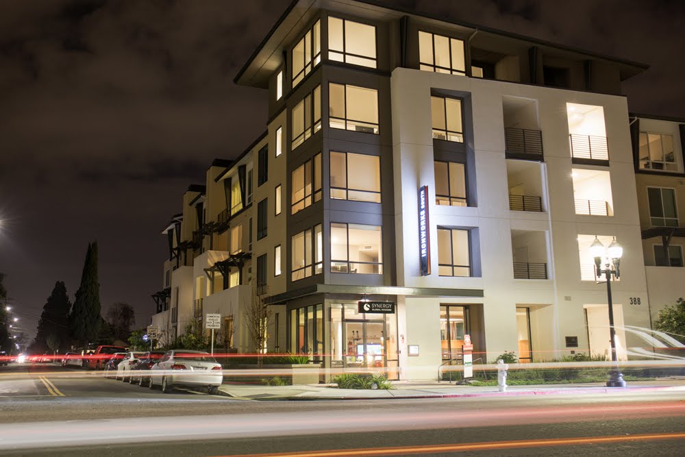 Modern multi-story building with illuminated windows and signage at night.