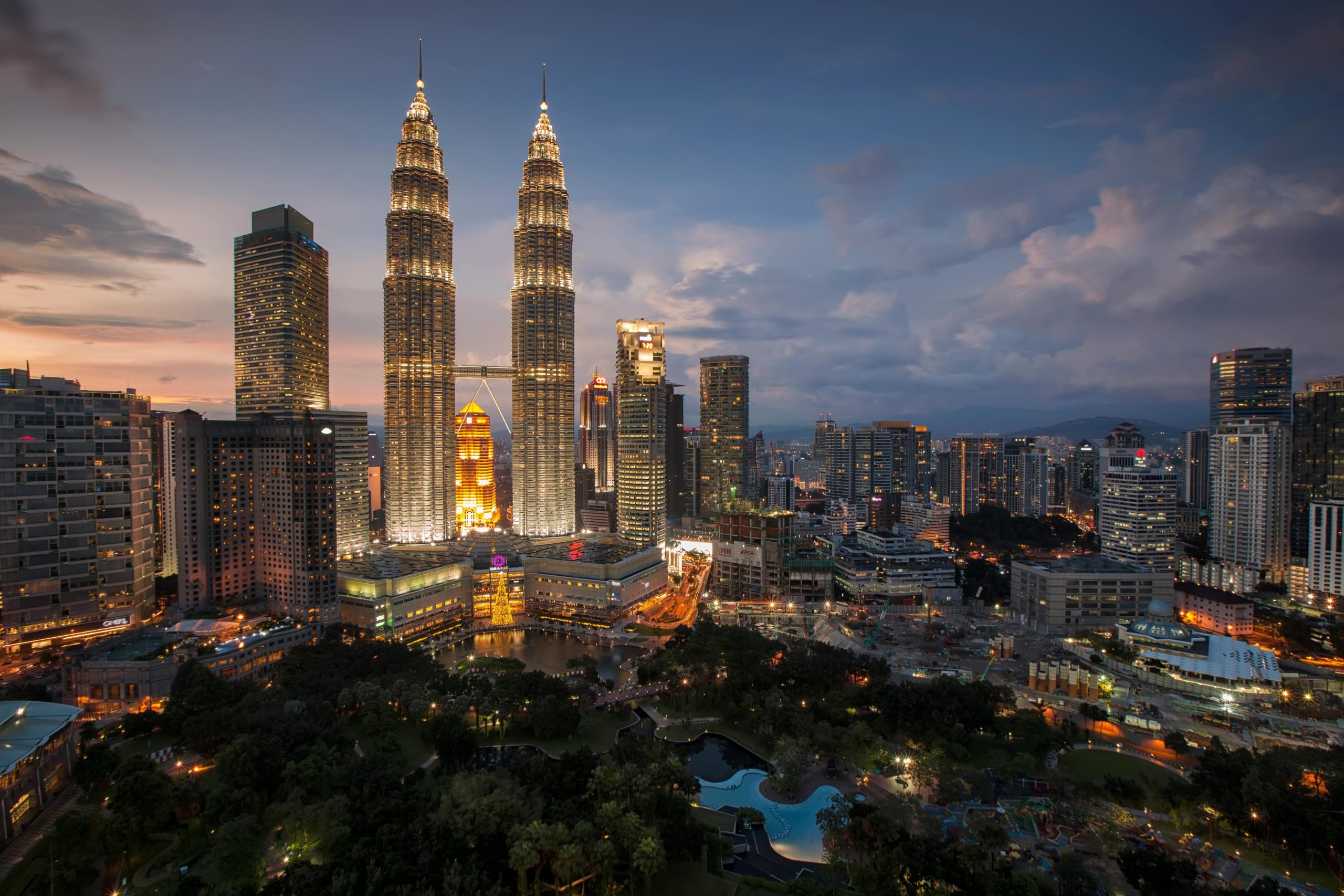 Kuala Lumpur skyline at dusk, featuring the illuminated Petronas Twin Towers and cityscape.