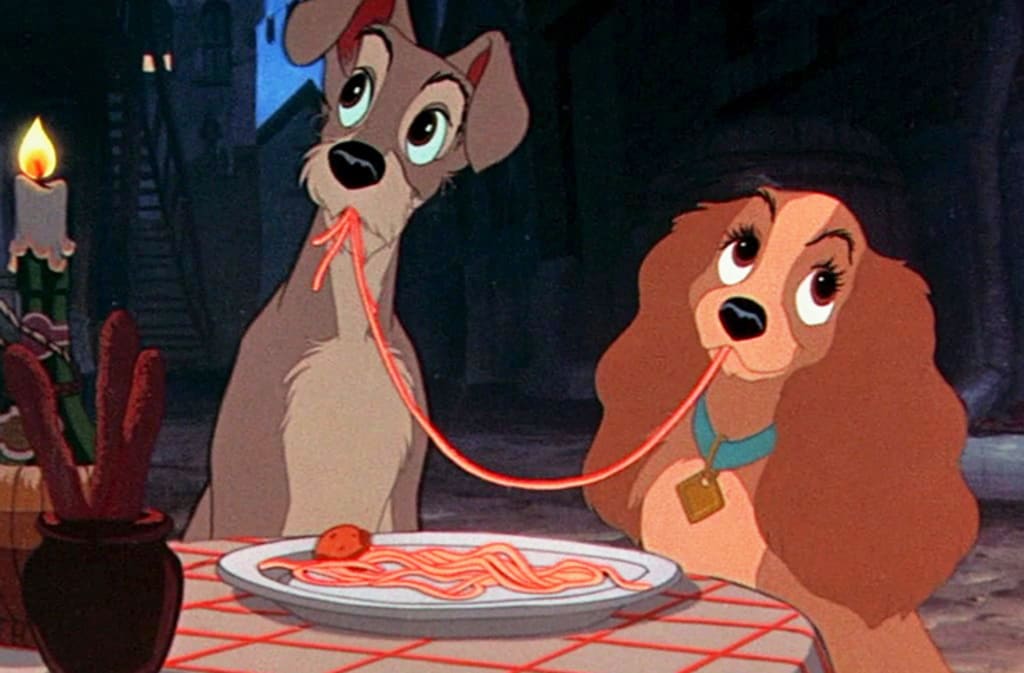Two animated dogs share a strand of spaghetti in a romantic candlelit setting.