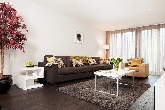 Modern living room with dark flooring, neutral furniture, and vibrant accents.