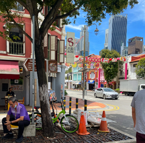 A vibrant urban street scene with colorful buildings, greenery, and modern skyscrapers in the background.