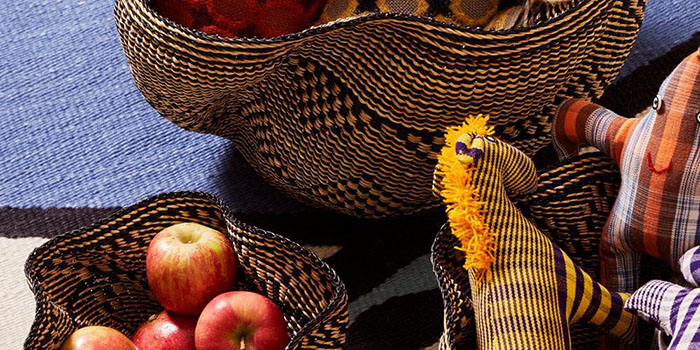 Woven baskets hold apples and toys, placed on a textured surface with vibrant patterns.