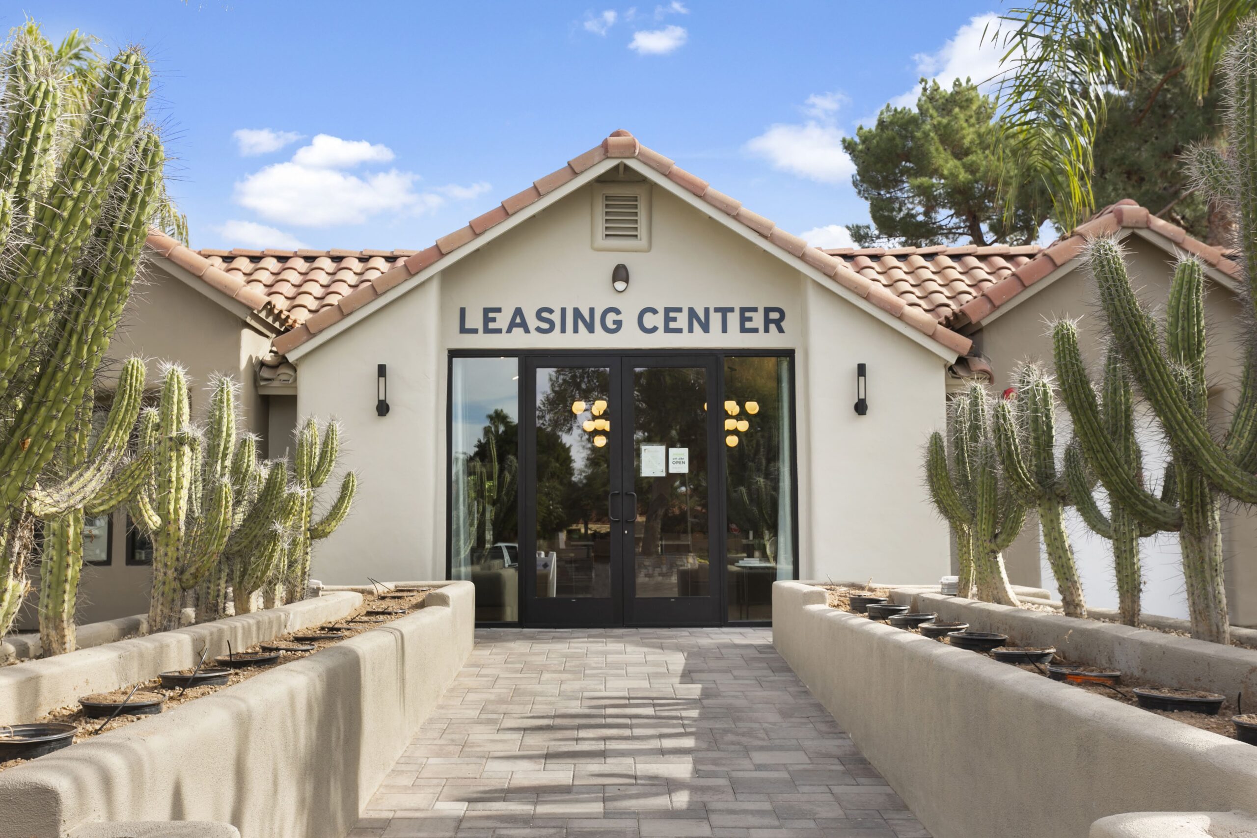 Leasing center entrance with modern design, cacti landscaping, and terracotta roof tiles.