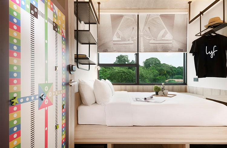A modern, compact bedroom with vibrant decor, large windows, and minimalist furnishings.