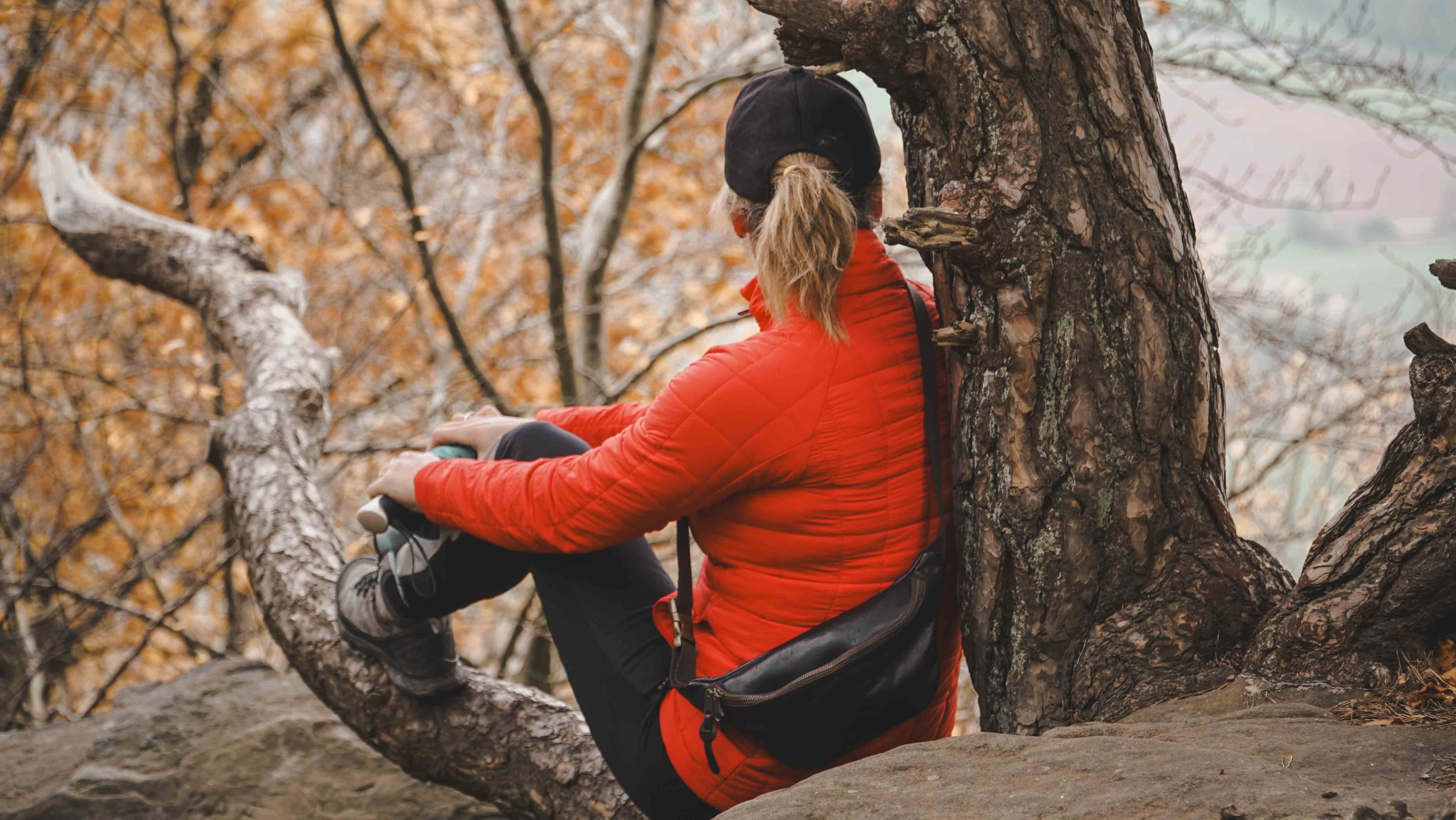 Frau sitzt auf einem Baumstamm