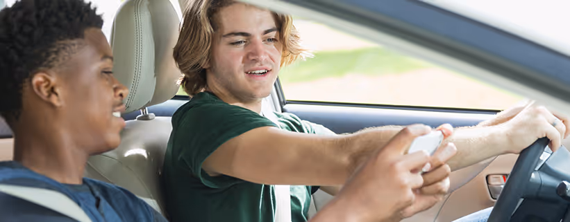 A man driving and looking at other person's phone 