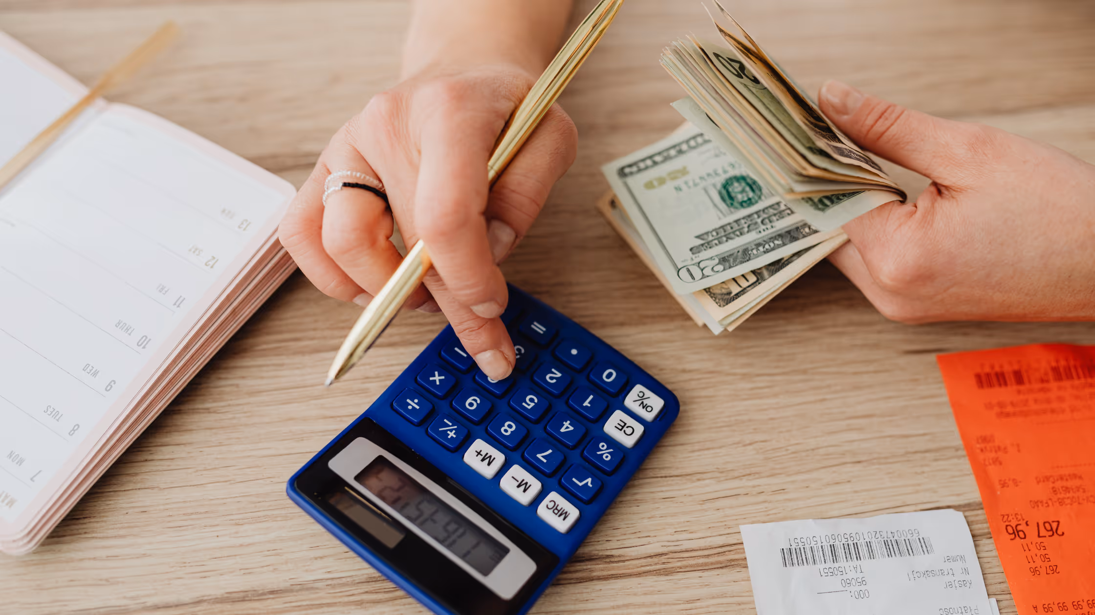 Hands holding money and using a calculator 