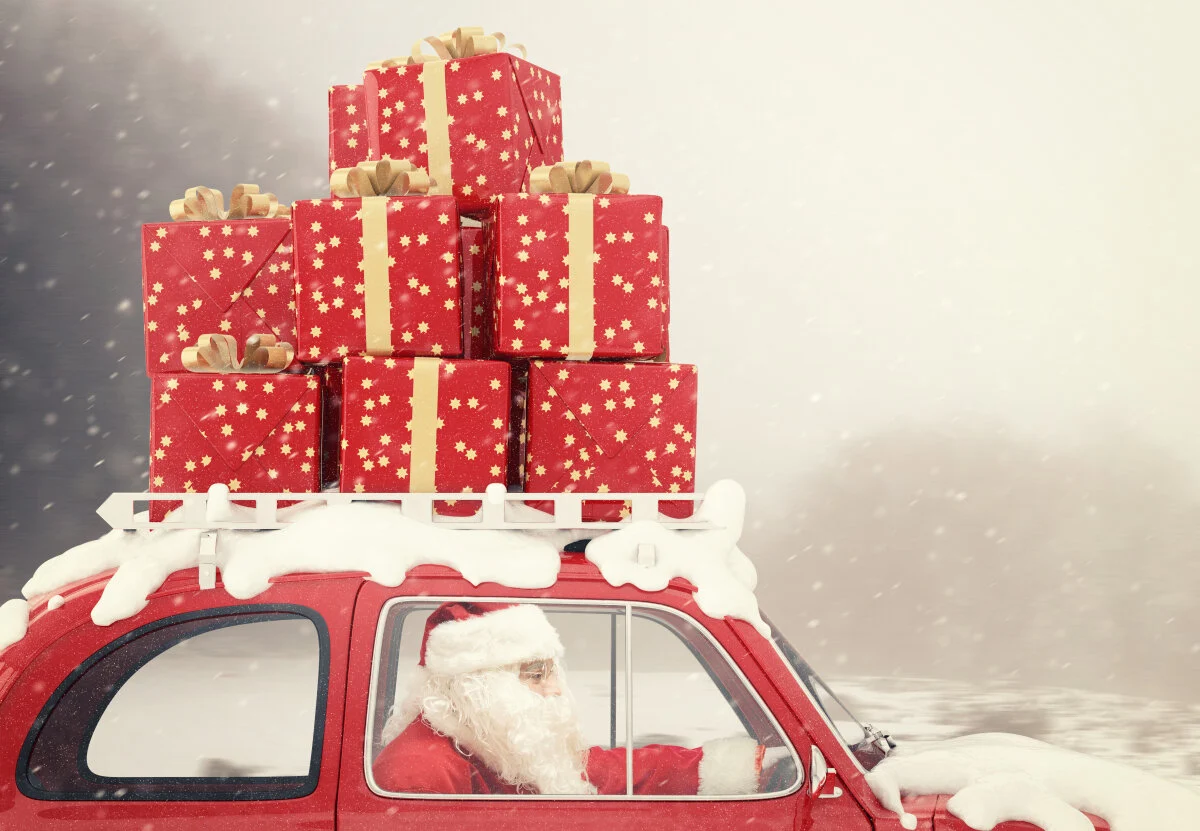 Santa in red car with stacked gifts on roof
