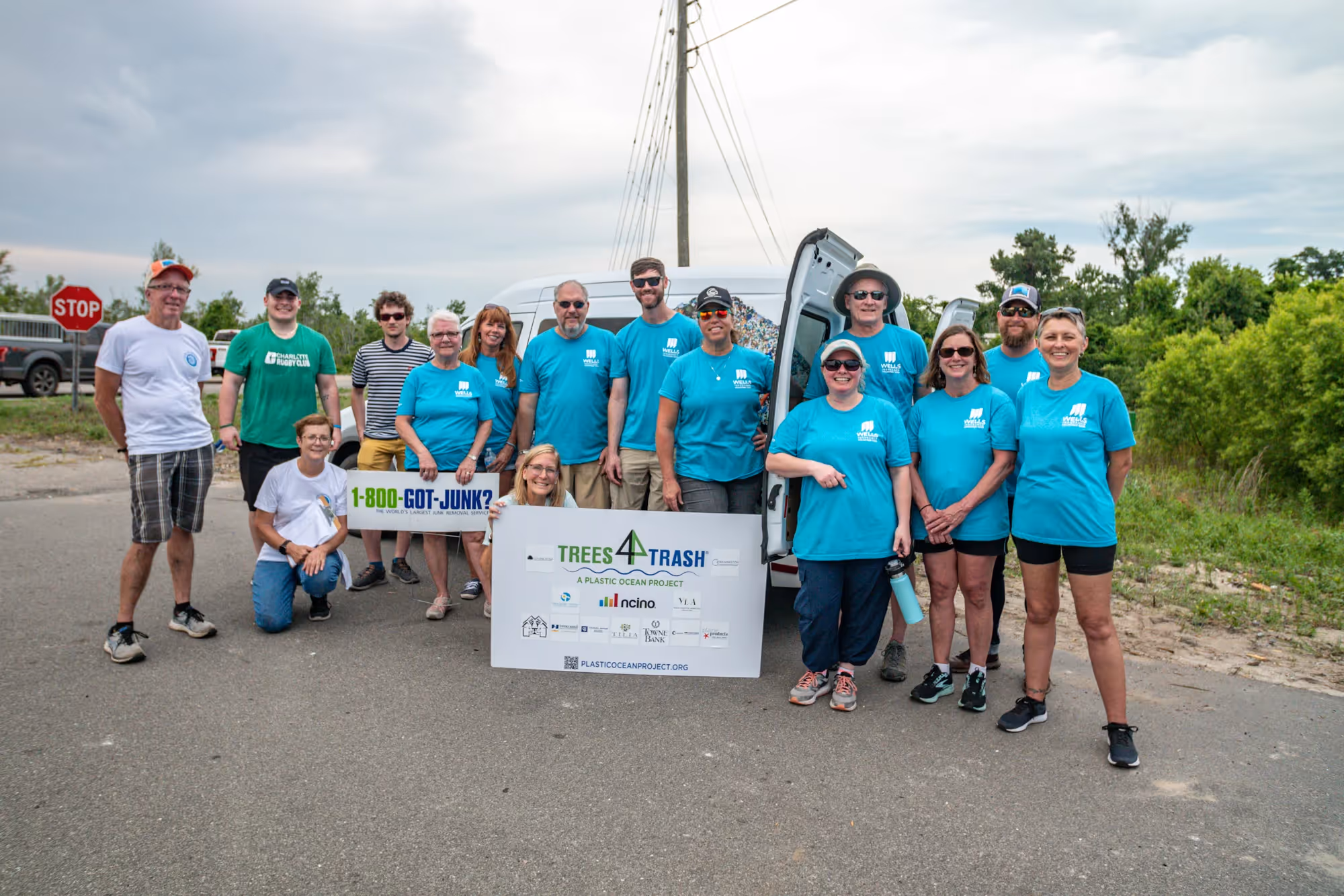 Wells insurance team poses with Trees 4 Trash banner.