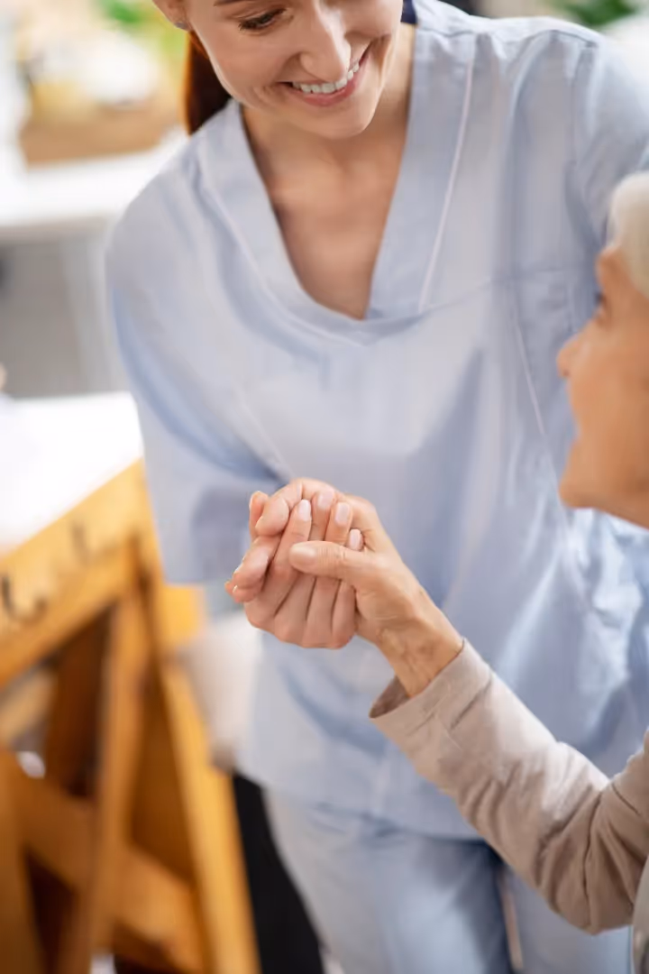 A photograph of a smiling nurse assisting an elderly woman