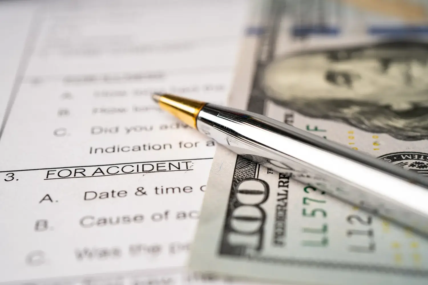 Accident claim form with pen and cash.