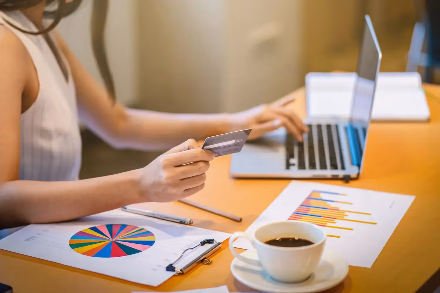 Woman paying online with credit card at desk.
