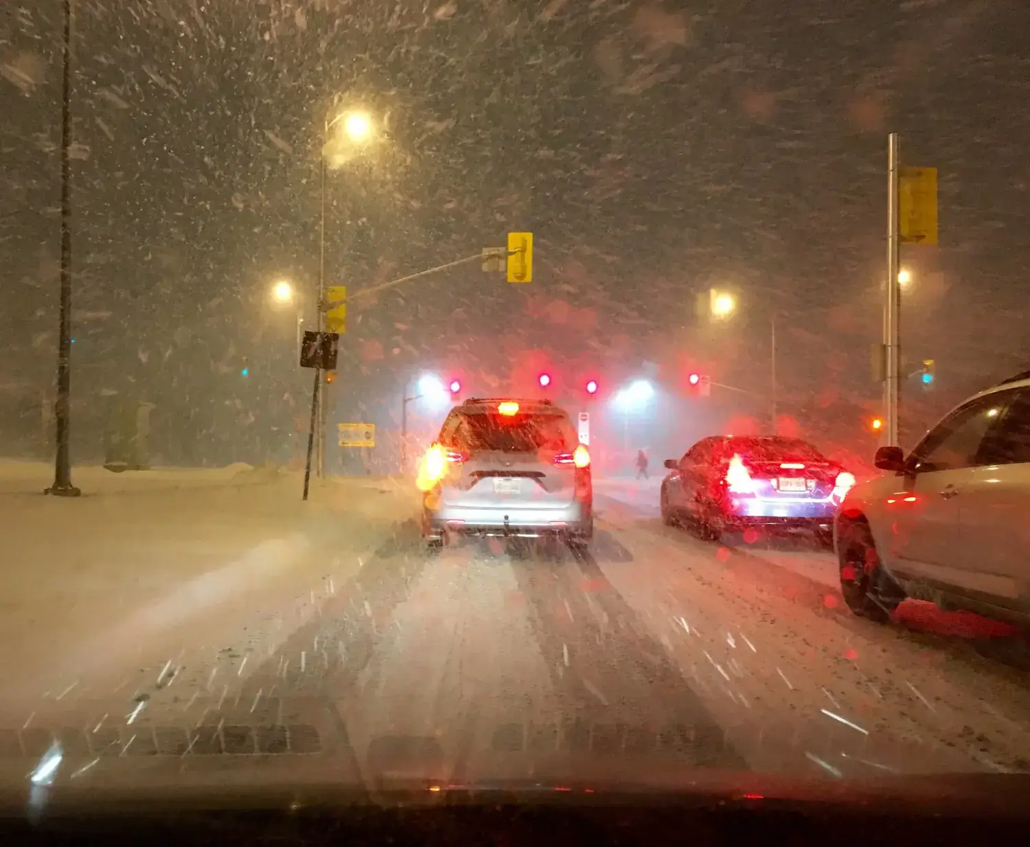 Cars stopped at a red light on a snowy night