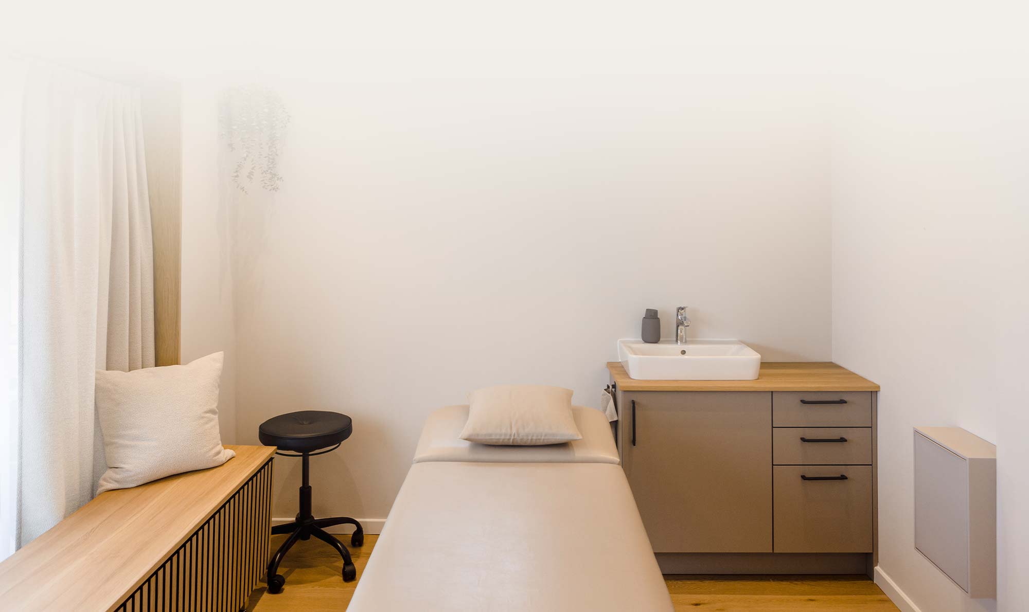 Behandlungsraum mit Waschbecken und Therapieliege