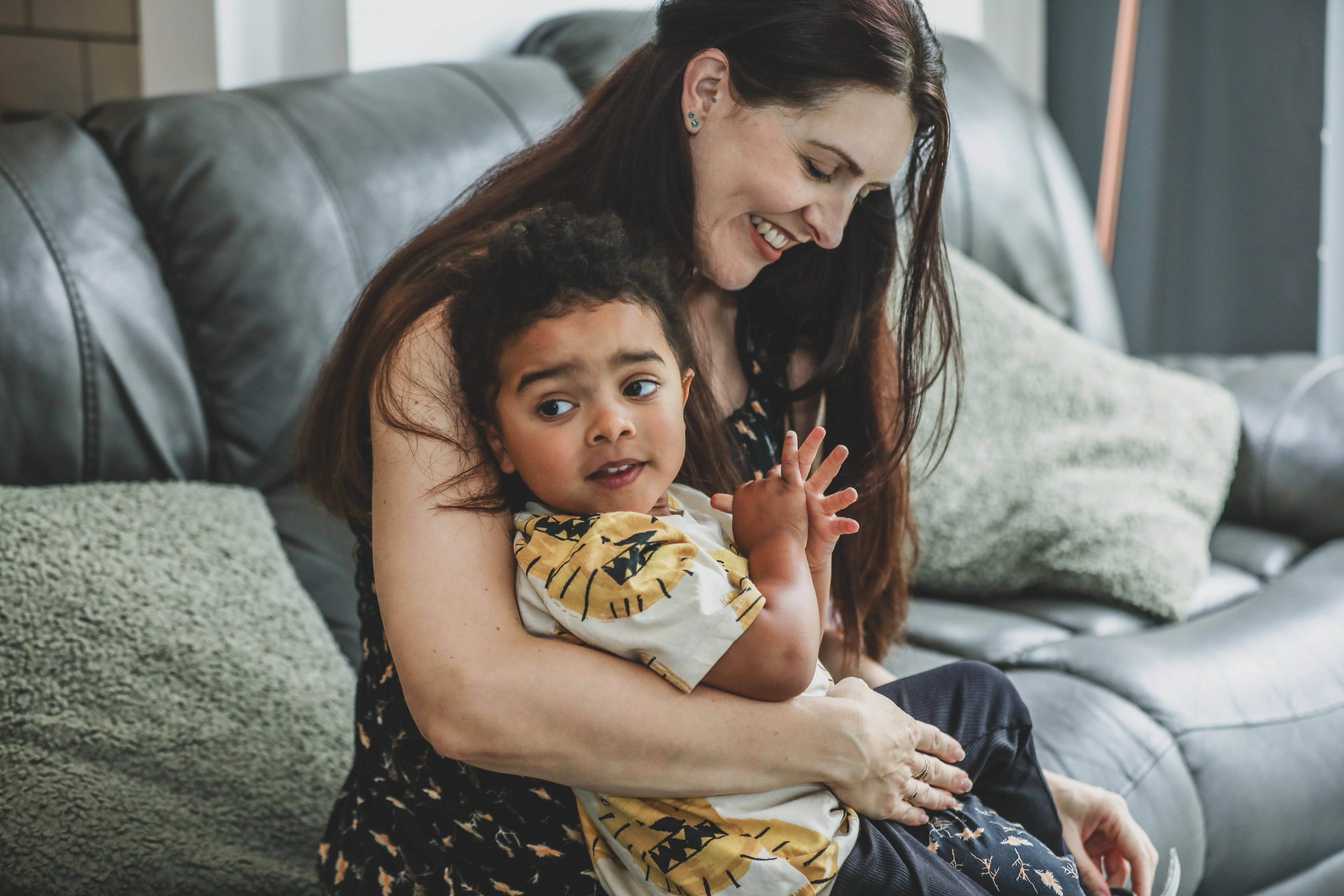 Mother and child cuddling together on a sofa at home