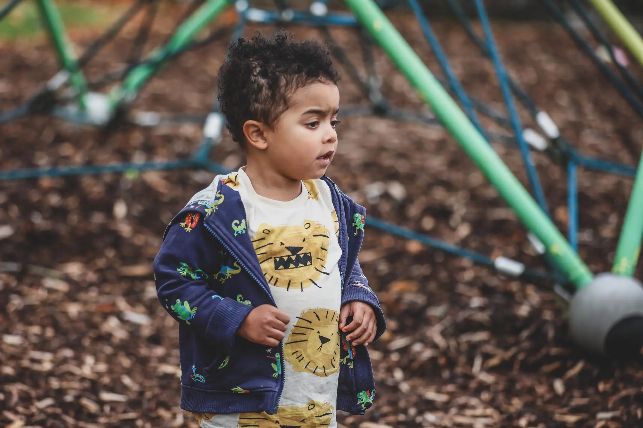 Toddler exploring a playground surrounded by colourful equipment