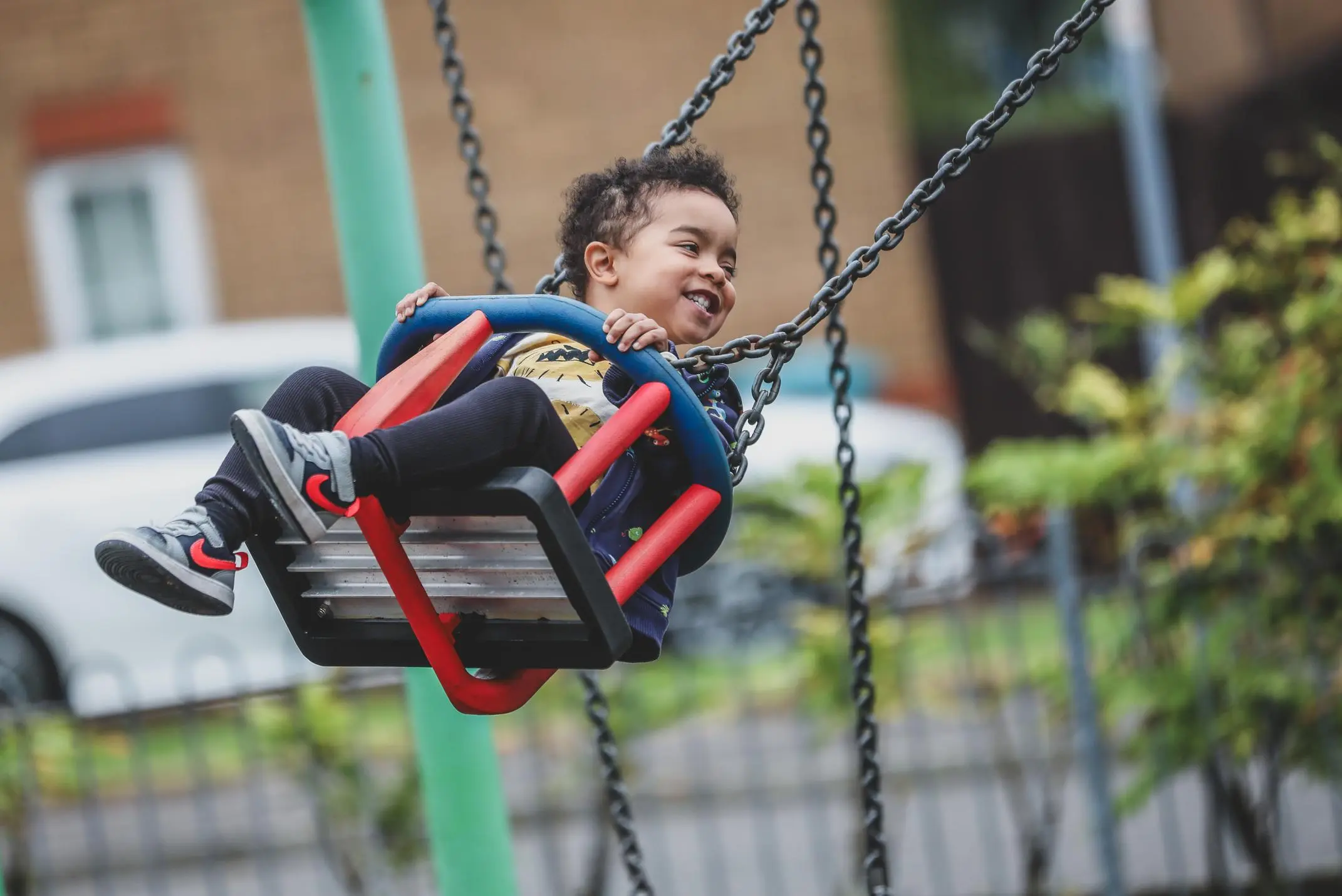 Smiling child swinging high on a playground swing