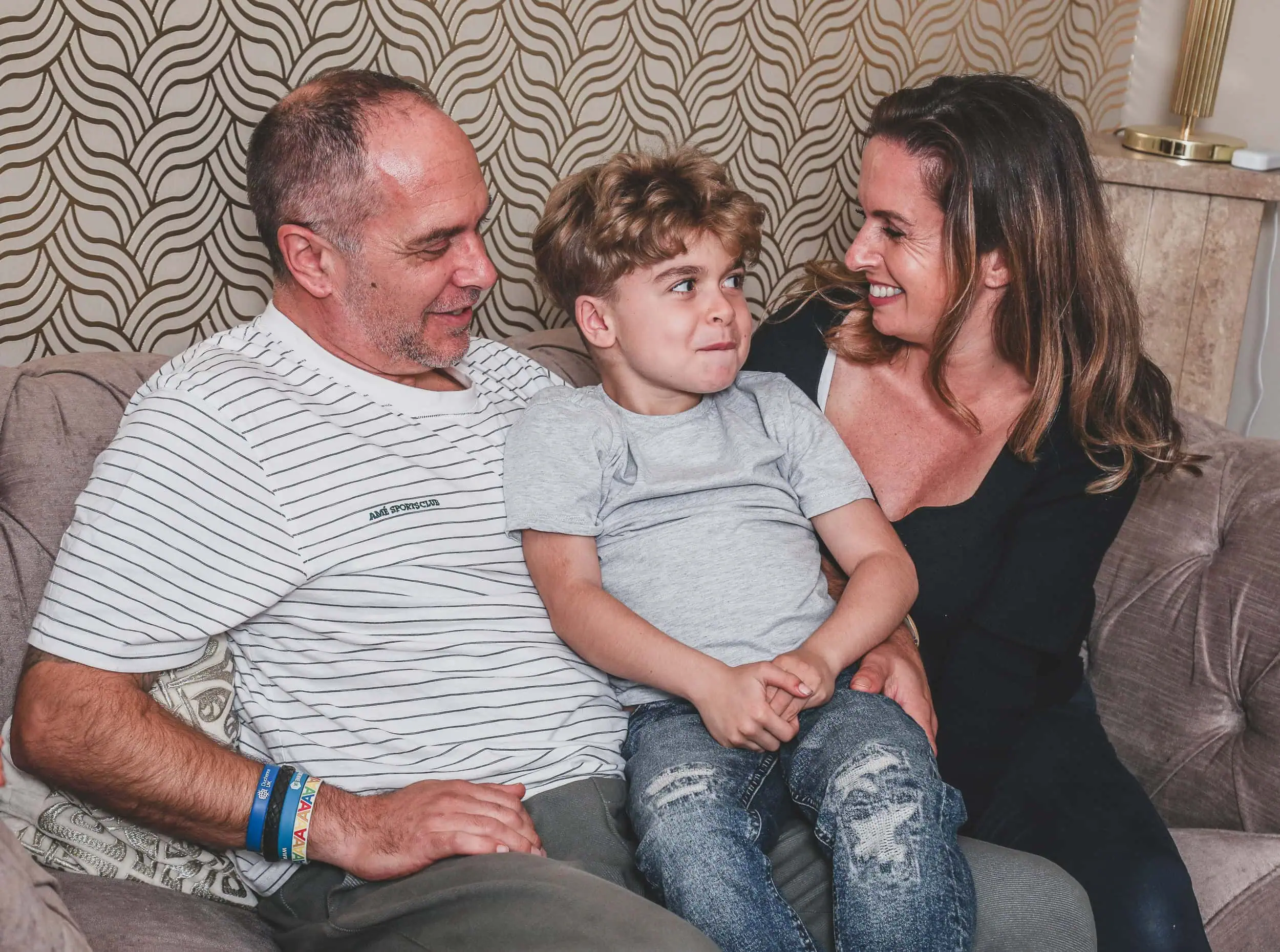 Family sitting close together on a couch, smiling at the camera