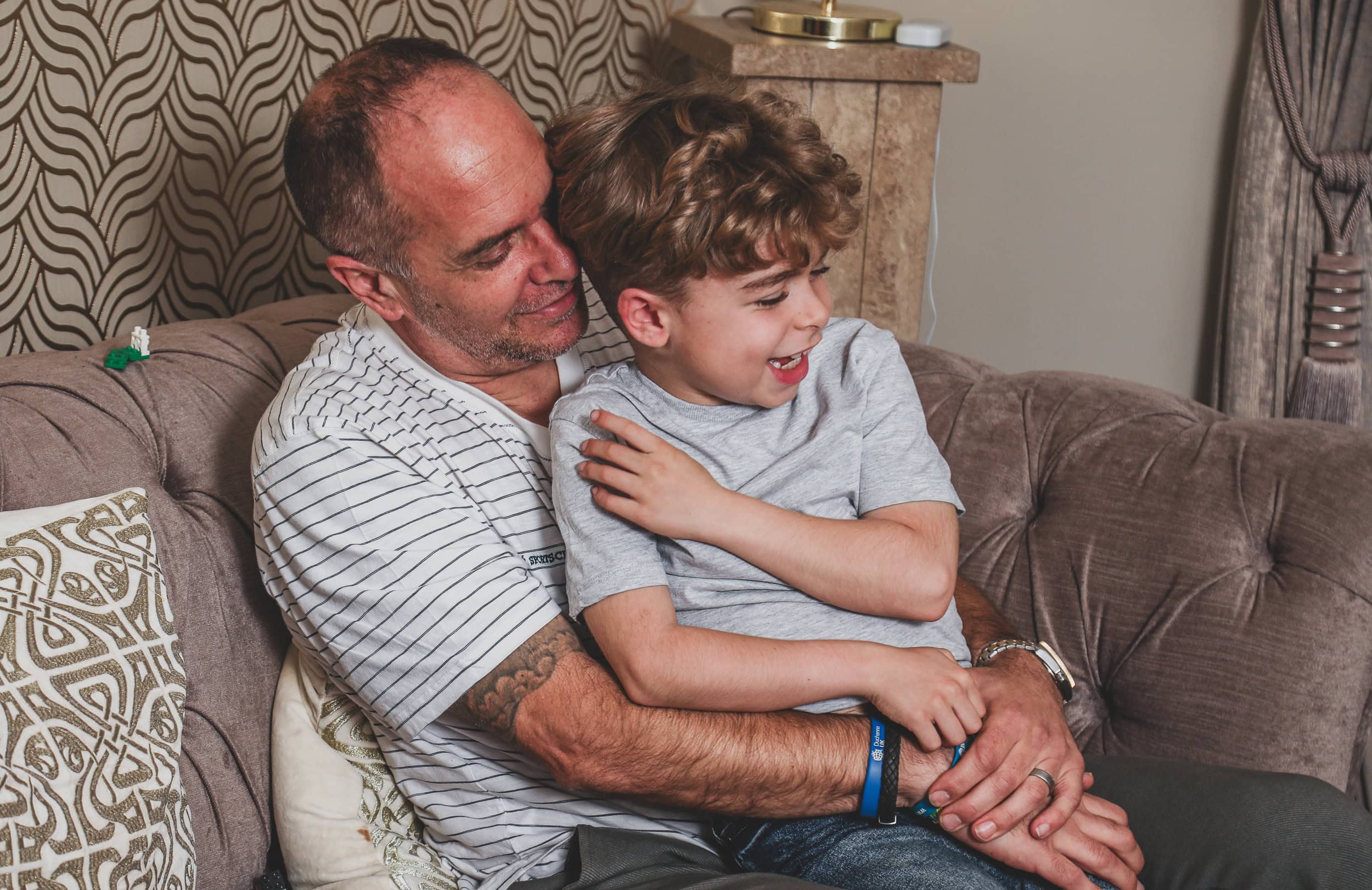 Man and boy cuddling together on a sofa in a cosy room