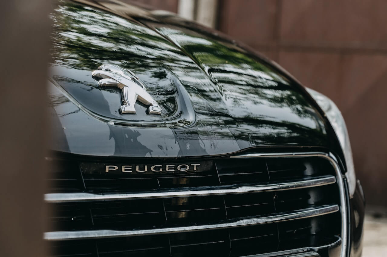 Close-up of a black car's front grille featuring the Peugeot lion emblem and brand name.