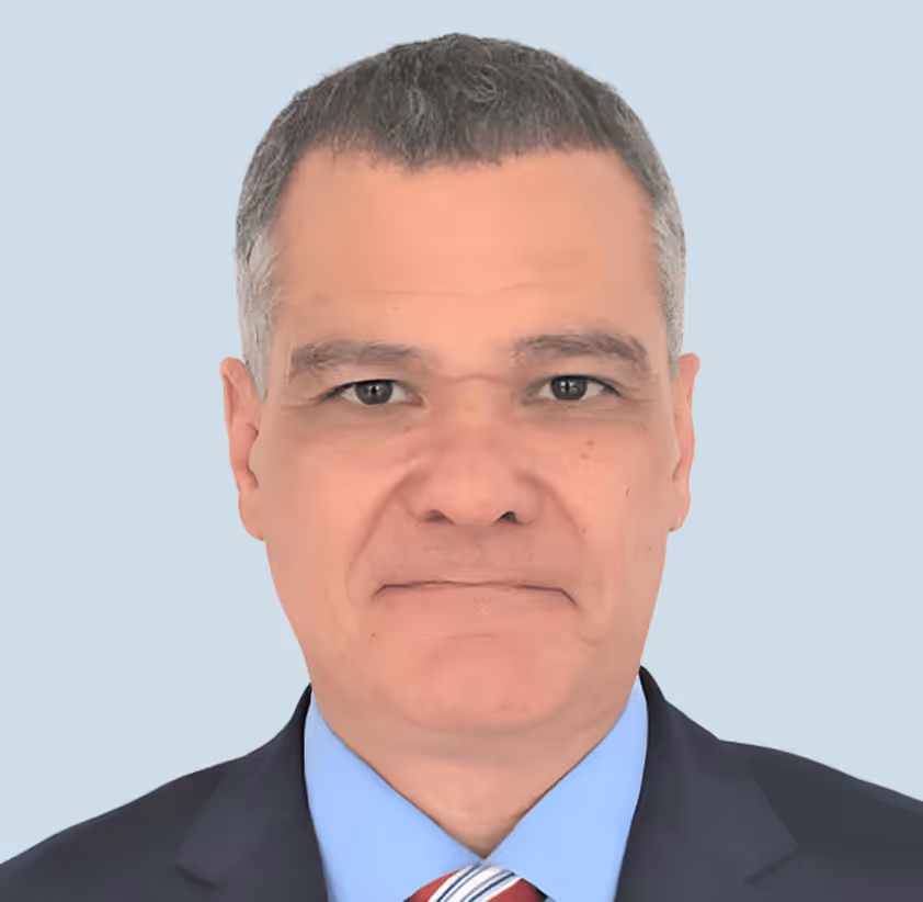 Portret van een man tegen een lichtblauwe achtergrond die recht in de camera kijkt.