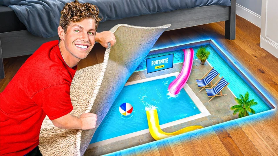 A man in a red shirt lifts a carpet to reveal a hidden swimming pool below the floor with two waterslides, two striped lounge chairs, palm trees, a beach ball, and a screen displaying the Fortnite game logo.