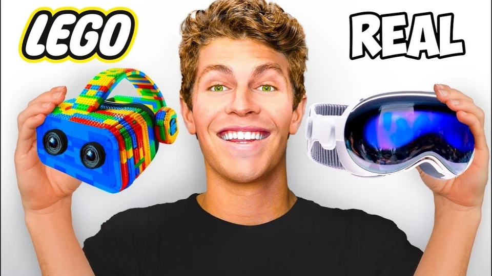 Smiling young man holding a LEGO virtual reality headset in his left hand and a real VR headset with blue lenses in his right hand, labeled LEGO and REAL respectively.