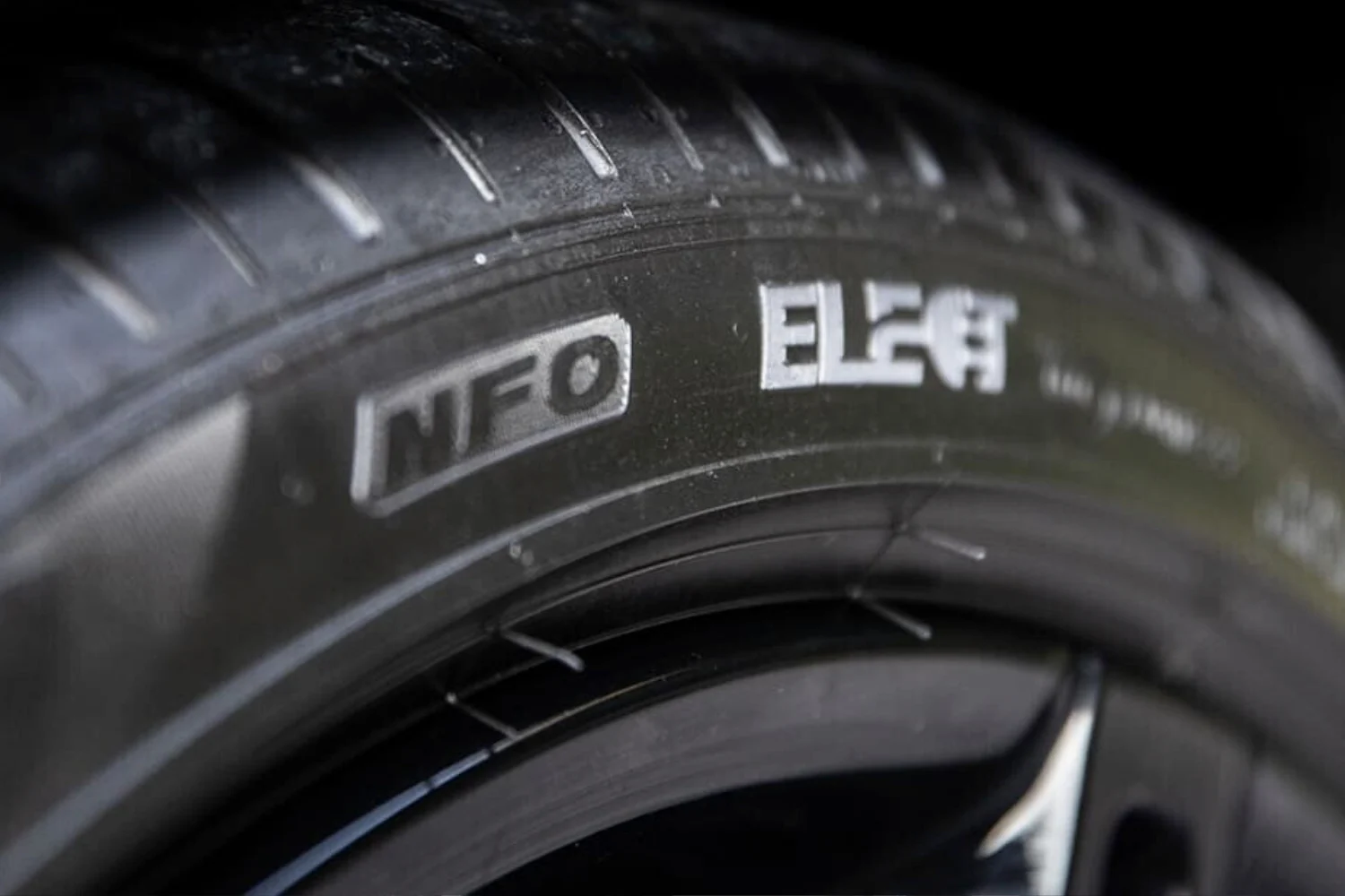 Conducteur installant des chaînes à neige sur un pneu de voiture dans un environnement enneigé