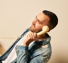 An image of a male model with an old telephone on his ear.