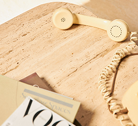 An image of an old telephone and Vogue magazine on a table. 